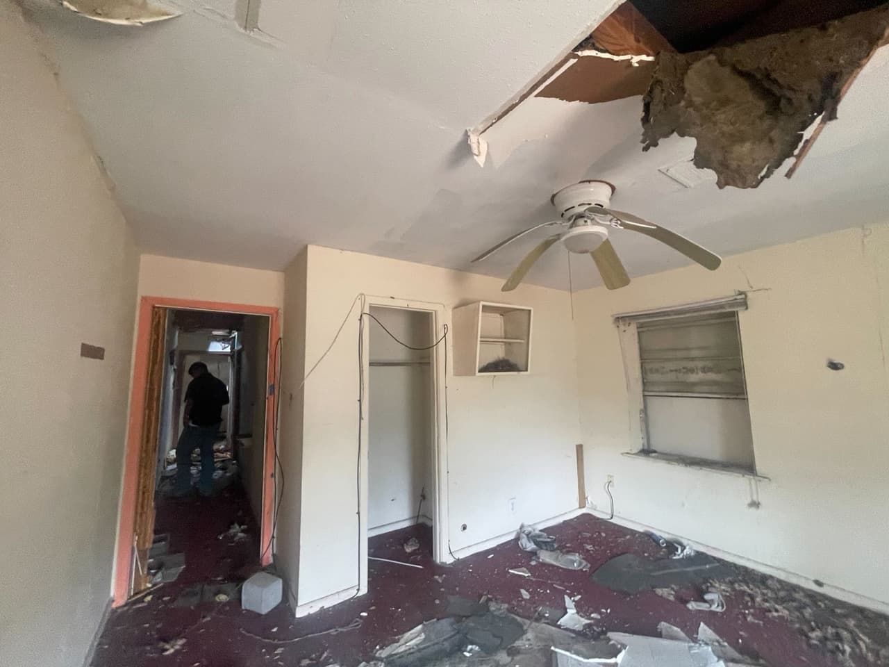 Bedroom before renovation with a collapsed ceiling and debris across the floor
